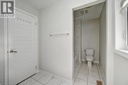 White panel door, chrome towel bar, white tile flooring, white window trim, and a built-in toilet - 