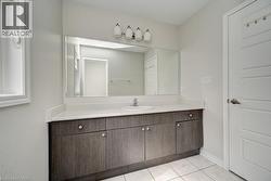 Long vanity with a single basin, wood-finish cabinetry, and a large mirror - 