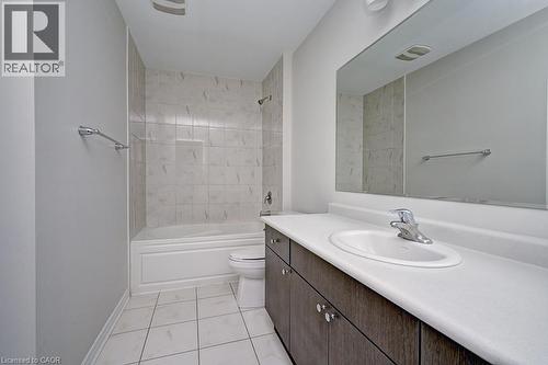 Bathroom featuring a white bathtub, tiled shower surround, large vanity mirror, and an integrated sink with a chrome faucet - 236 Ridge Road, Cambridge, ON 