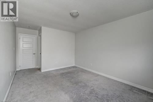 Neutral painted walls, grey carpet flooring, white trim, and a flush mount ceiling light fixture - 236 Ridge Road, Cambridge, ON 