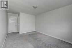Neutral painted walls, grey carpet flooring, white trim, and a flush mount ceiling light fixture - 
