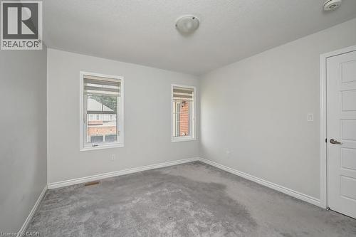 Neutral wall tones with gray carpeting, two windows with blinds, a flush mount ceiling light, and a paneled interior door - 236 Ridge Road, Cambridge, ON 