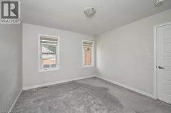 Neutral wall tones with gray carpeting, two windows with blinds, a flush mount ceiling light, and a paneled interior door - 