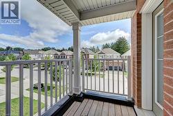 Balcony with wood-finish flooring, white railing, and brick wall - 