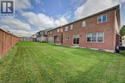 Expansive green lawn with a wood fence, brick exterior, and multiple windows - 
