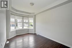 Bay window with multiple panes, dark wood-finish flooring, white trim, and a tray ceiling - 