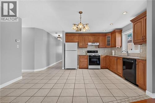 U-shaped kitchen with wood-finish cabinetry, light tile flooring, and a tile backsplash - 795 Tenth Avenue, Hamilton, ON 
