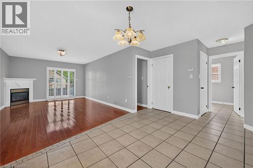 Hardwood-style flooring, fireplace with white mantel, white patio door, light gray walls, and light-toned tile flooring - 795 Tenth Avenue, Hamilton, ON 