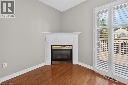 Corner fireplace with white mantel, wood-finish flooring, and white plantation shutters - 795 Tenth Avenue, Hamilton, ON 