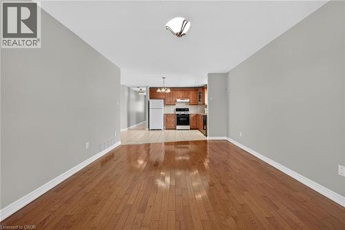 Wood-finish flooring throughout, light gray wall tones, ceiling-mounted light fixture, and a kitchen featuring wood cabinetry - 795 Tenth Avenue, Hamilton, ON 