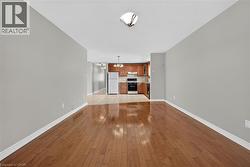 Wood-finish flooring throughout, light gray wall tones, ceiling-mounted light fixture, and a kitchen featuring wood cabinetry - 