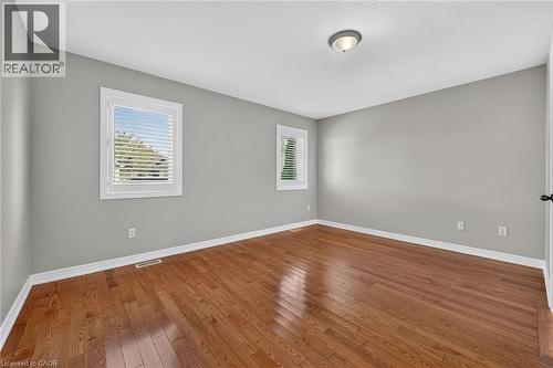 Hardwood flooring, two windows with blinds, gray wall paint, white trim, and a ceiling-mounted light fixture - 795 Tenth Avenue, Hamilton, ON 