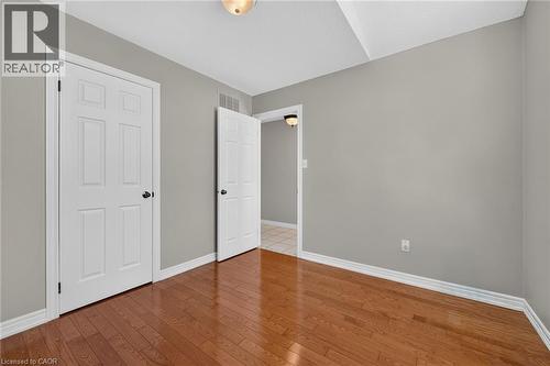 Wood-finish flooring, light gray wall paint, white trim, white six-panel interior doors, and a ceiling-mounted light fixture - 795 Tenth Avenue, Hamilton, ON 