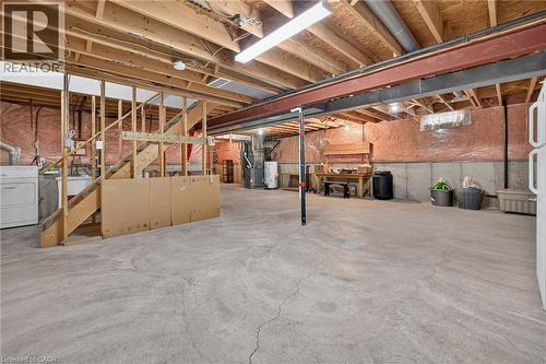 Unfinished basement with exposed ceiling joists, concrete flooring, and a utility sink - 795 Tenth Avenue, Hamilton, ON 