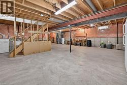 Unfinished basement with exposed ceiling joists, concrete flooring, and a utility sink - 