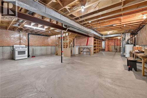 Expansive unfinished basement featuring concrete flooring, exposed wood ceiling joists, and a built-in shelving unit - 795 Tenth Avenue, Hamilton, ON 