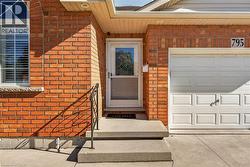 Brick exterior with an arched window, white garage door, concrete steps, and a wrought iron handrail - 