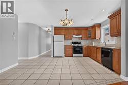 U-shaped kitchen with wood-finish cabinetry, light tile flooring, and a tile backsplash - 