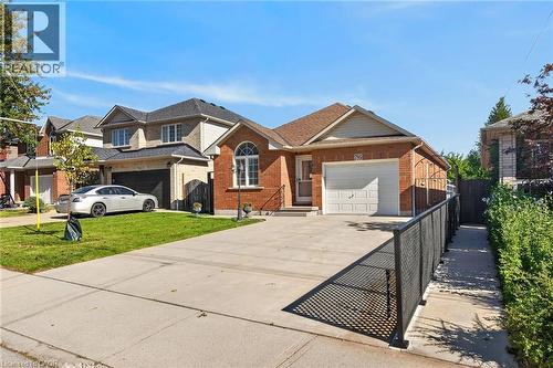 Brick exterior with an arched window, attached garage, and a concrete driveway - 795 Tenth Avenue, Hamilton, ON 