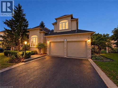 Stucco and stone exterior with arched windows, a two-car garage, and a paved driveway - 74 Davidson Boulevard, Dundas, ON 