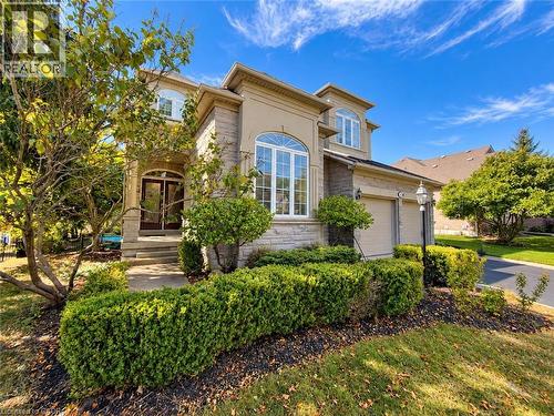 Stucco and stone exterior, arched windows, covered entryway, mature landscaping, and an attached two-car garage - 74 Davidson Boulevard, Dundas, ON 