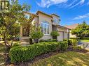 Stucco and stone exterior, arched windows, covered entryway, mature landscaping, and an attached two-car garage - 74 Davidson Boulevard, Dundas, ON 
