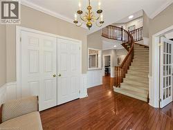 Grand foyer featuring hardwood flooring, a curved staircase with wood banister, wainscoting, and a brass chandelier - 