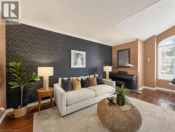 Hardwood-finish flooring, accent wall with patterned wallpaper, crown molding, and an arched window - 