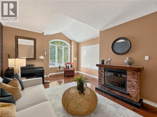 Vaulted ceiling, wood-finish flooring, electric fireplace with stacked stone surround, wood mantel, and large arched window - 74 Davidson Boulevard, Dundas, ON 