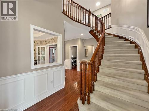 Curved staircase with wood-finish railing, carpeted treads, and wainscoting, complemented by wood-finish flooring and a wall pass-through - 74 Davidson Boulevard, Dundas, ON 