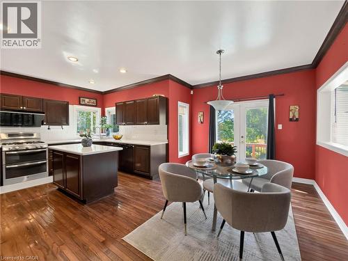 Kitchen featuring dark wood cabinetry, stainless steel appliances, a center island with countertop, and wood-finish flooring - 74 Davidson Boulevard, Dundas, ON 