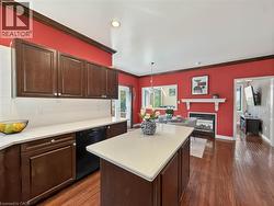 Kitchen featuring dark wood cabinetry, white countertops, white tile backsplash, and a central island - 