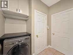 Laundry area featuring overhead cabinetry, a wall-mounted drying rack, a black countertop, and tile flooring - 