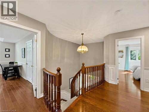 Hardwood flooring, wood banister with white spindles, curved wall detail, wainscoting, and a decorative pendant light fixture - 74 Davidson Boulevard, Dundas, ON 
