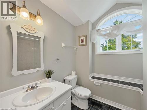 Bathroom featuring a white vanity with an integrated sink, a decorative mirror, and a toilet - 74 Davidson Boulevard, Dundas, ON 