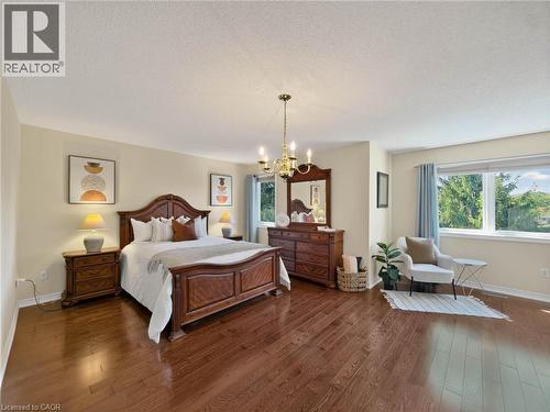 Expansive room featuring rich wood-finish flooring, a decorative chandelier, and large windows - 74 Davidson Boulevard, Dundas, ON 