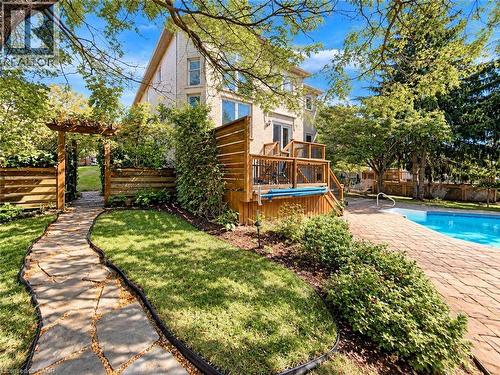 Outdoor living space featuring a swimming pool, wood deck, stone patio, and natural stone pathway - 74 Davidson Boulevard, Dundas, ON 