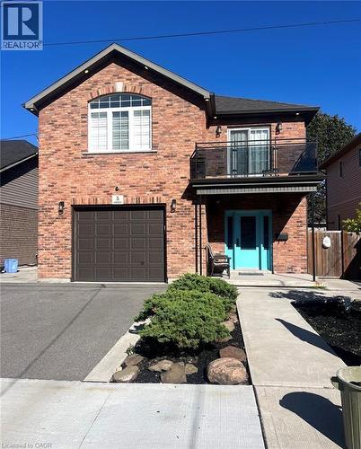 Brick facade with a prominent arched window, integrated garage, and a second-story balcony with glass railing - 5 Arden Avenue, Hamilton, ON 