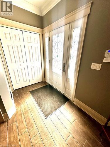 Entryway featuring wood-finish tile flooring, a decorative glass entry door with frosted sidelights, and a bifold door storage closet - 5 Arden Avenue, Hamilton, ON 