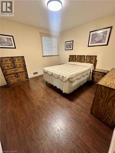 Wood-finish flooring throughout, window with white plantation shutters, and a flush-mount ceiling light fixture - 5 Arden Avenue, Hamilton, ON 