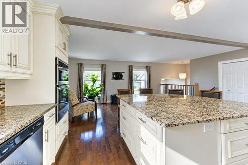 Kitchen featuring a large island with stone countertops, integrated double oven, white cabinetry with silver-tone hardware, and wood-finish flooring - 34 Wayne Drive, Kitchener, ON 
