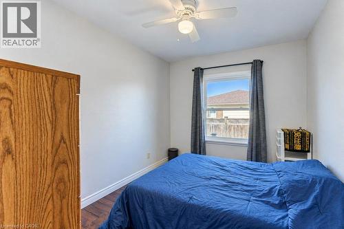 White walls, wood-finish flooring, ceiling fan with integrated lighting, window with drapes, and a wooden door - 34 Wayne Drive, Kitchener, ON 