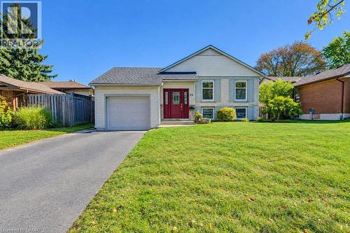 Great curb appeal featuring brick and siding, a two-car driveway, attached garage, and a red front entry door - 34 Wayne Drive, Kitchener, ON 