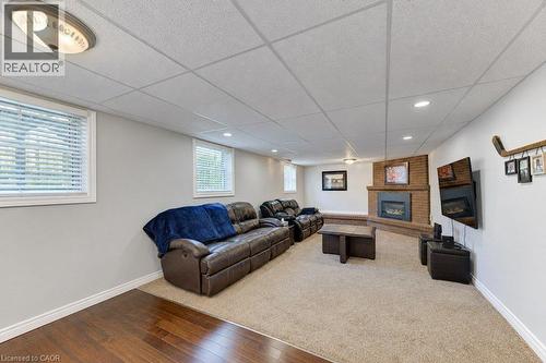 Recessed lighting, brick fireplace with mantel, two windows, wood-finish flooring, and carpeted area - 34 Wayne Drive, Kitchener, ON 