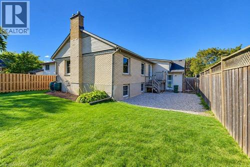 Brick exterior with a prominent chimney, wood-paneled siding, and a rear wooden deck - 34 Wayne Drive, Kitchener, ON 