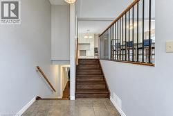 Entryway with tile flooring, wood-finish stairs, and metal balusters - 