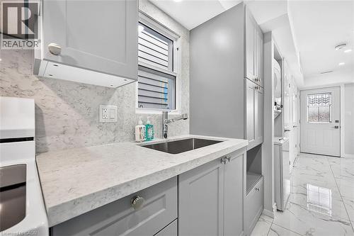 Light gray cabinetry, integrated sink, stone-finish countertop, coordinating backsplash, and tile flooring - 4 Albemarle Street, Hamilton, ON 