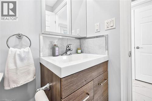 Wood-finish vanity with integrated sink, chrome faucet, and mirrored medicine cabinet - 4 Albemarle Street, Hamilton, ON 