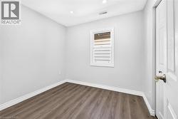 Recessed ceiling lighting, wood-finish flooring, white window trim, and a paneled interior door - 