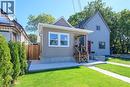 Exterior featuring horizontal siding, a covered porch with dark railings, a red entry door, a paved driveway, and mature landscaping - 4 Albemarle Street, Hamilton, ON 